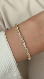 Gold oval and round cubic zirconia tennis bracelet moving naturally on the wrist.