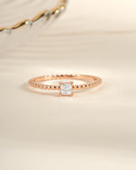 Rose gold princess cut ring with a beaded band from Sami Jewels, showcasing a sparkling central gemstone and intricate band detail.