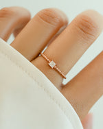 Elegant princess cut ring with beaded band by Sami Jewels, featuring a rose-colored gemstone and intricate band details.