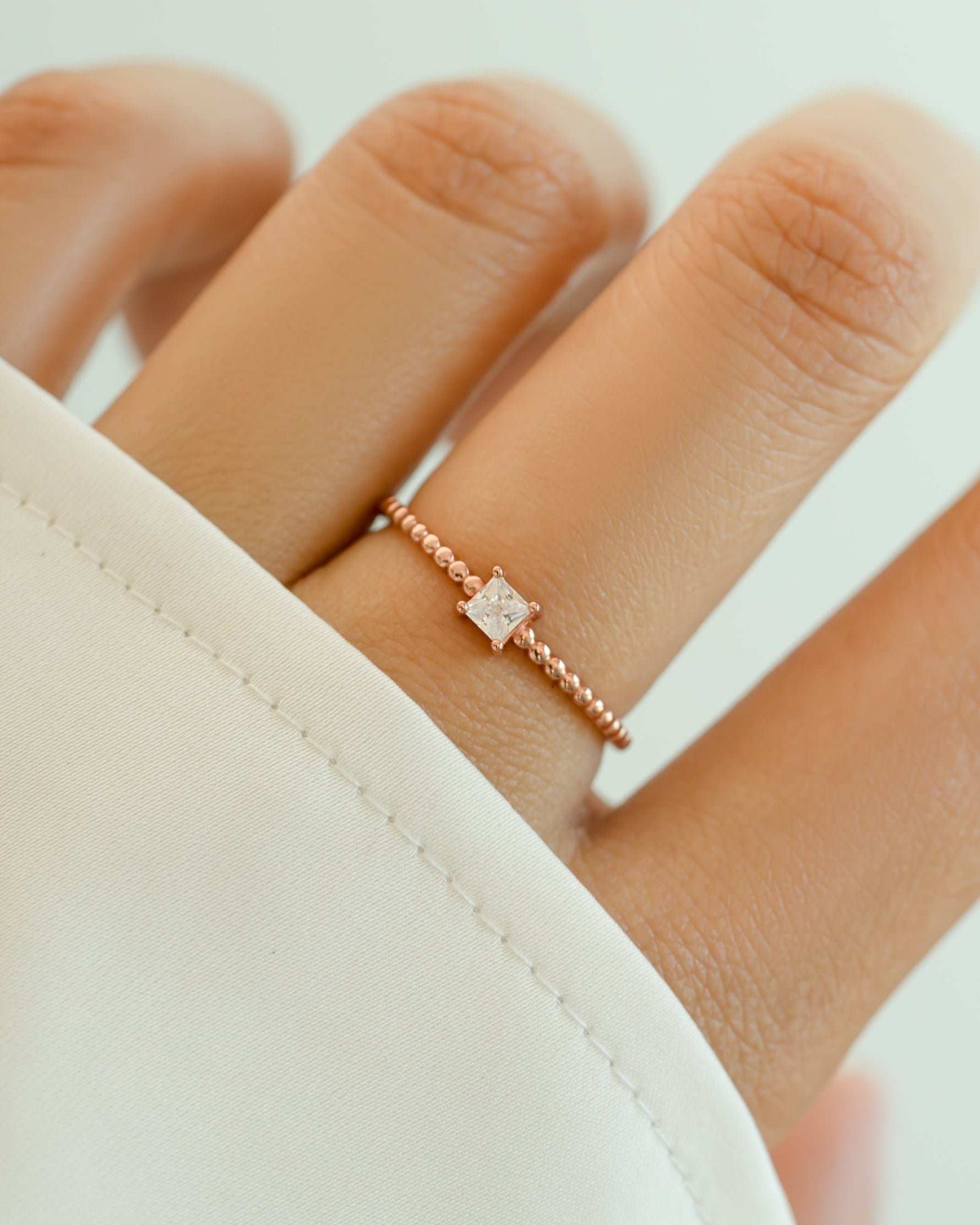 Elegant princess cut ring with beaded band by Sami Jewels, featuring a rose-colored gemstone and intricate band details.