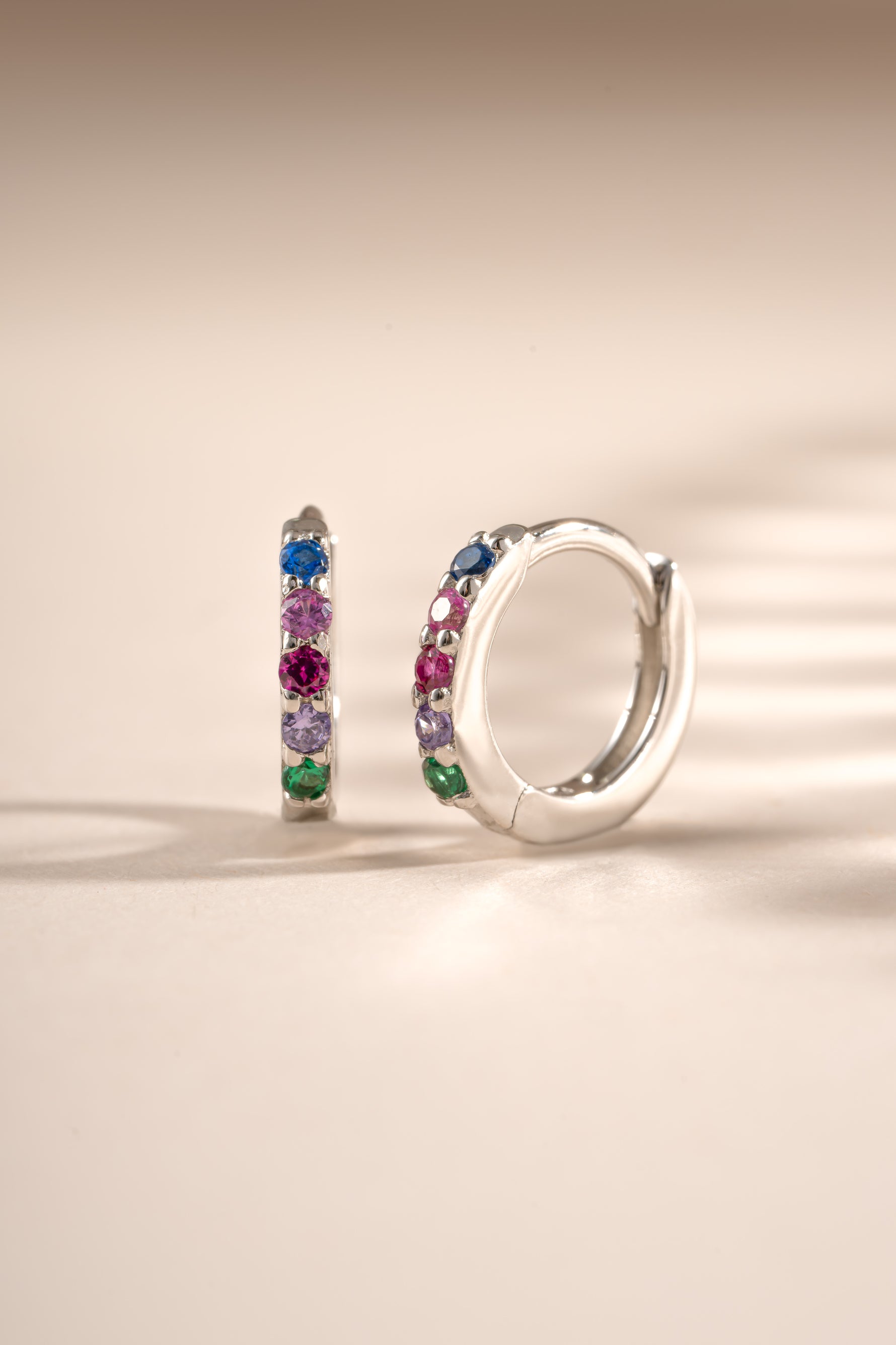 Sterling silver 7mm rainbow studded huggie earrings by Sami Jewels, featuring colorful rainbow accents and a secure hoop design.
