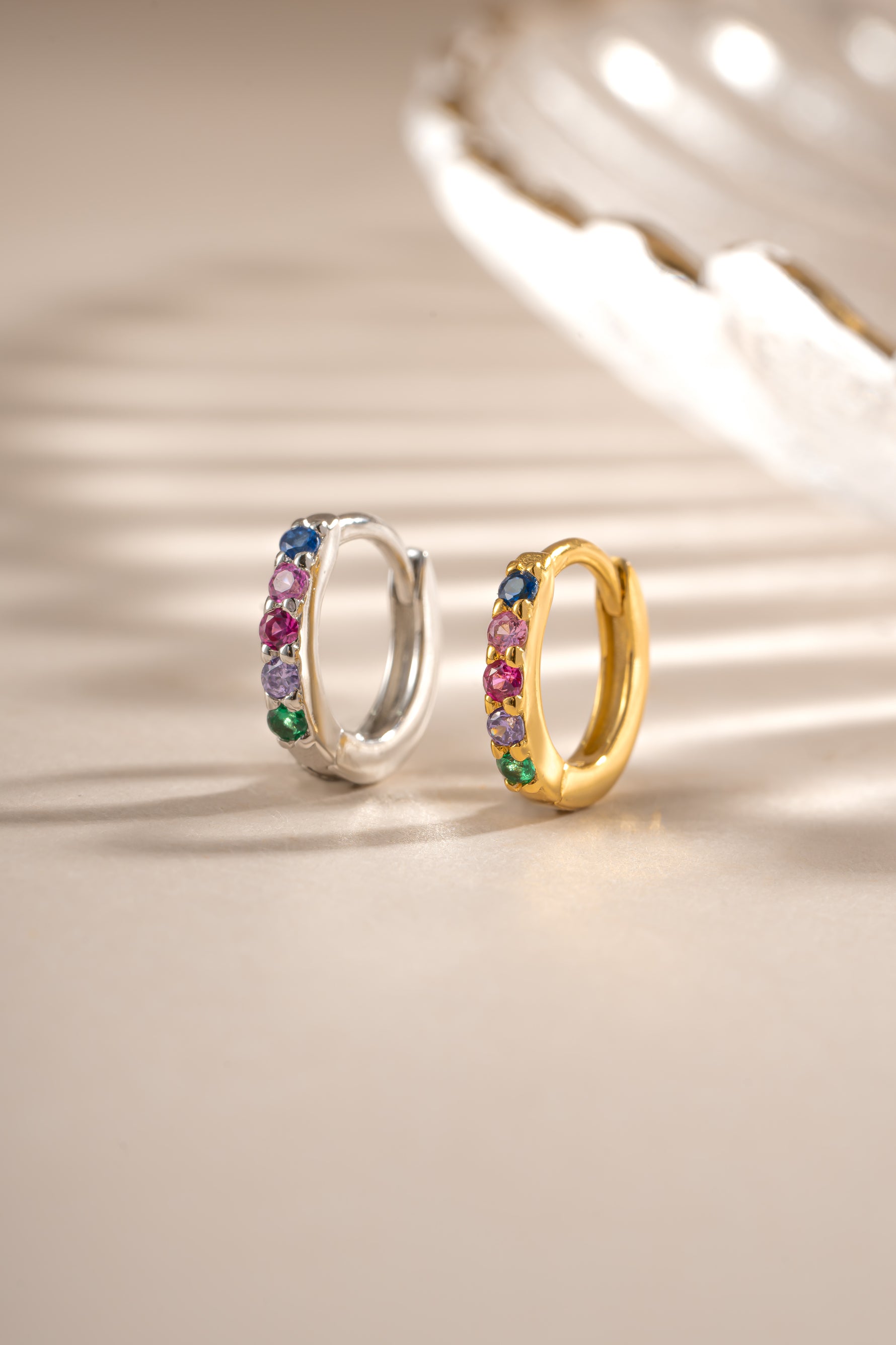 Rainbow-studded 7mm sterling silver and gold huggie earrings by Sami Jewels, showcasing colorful rainbow designs.