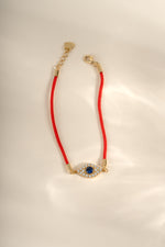 Close-up of Sami Jewels red string evil eye bracelet featuring a gold evil eye charm on a vibrant red string.
