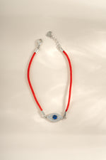 Red string evil eye bracelet by Sami Jewels featuring sterling silver accents, designed to ward off negative energy.