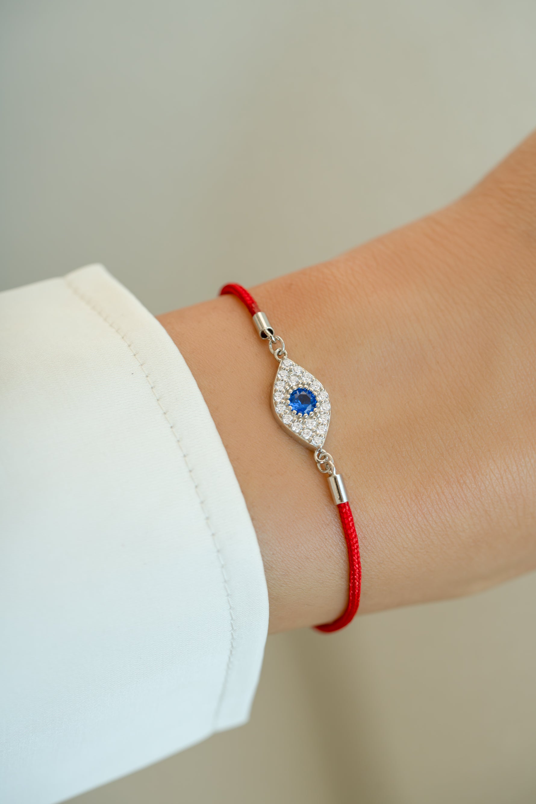 Red string evil eye bracelet from Sami Jewels featuring a sterling silver evil eye charm on a vibrant red string.