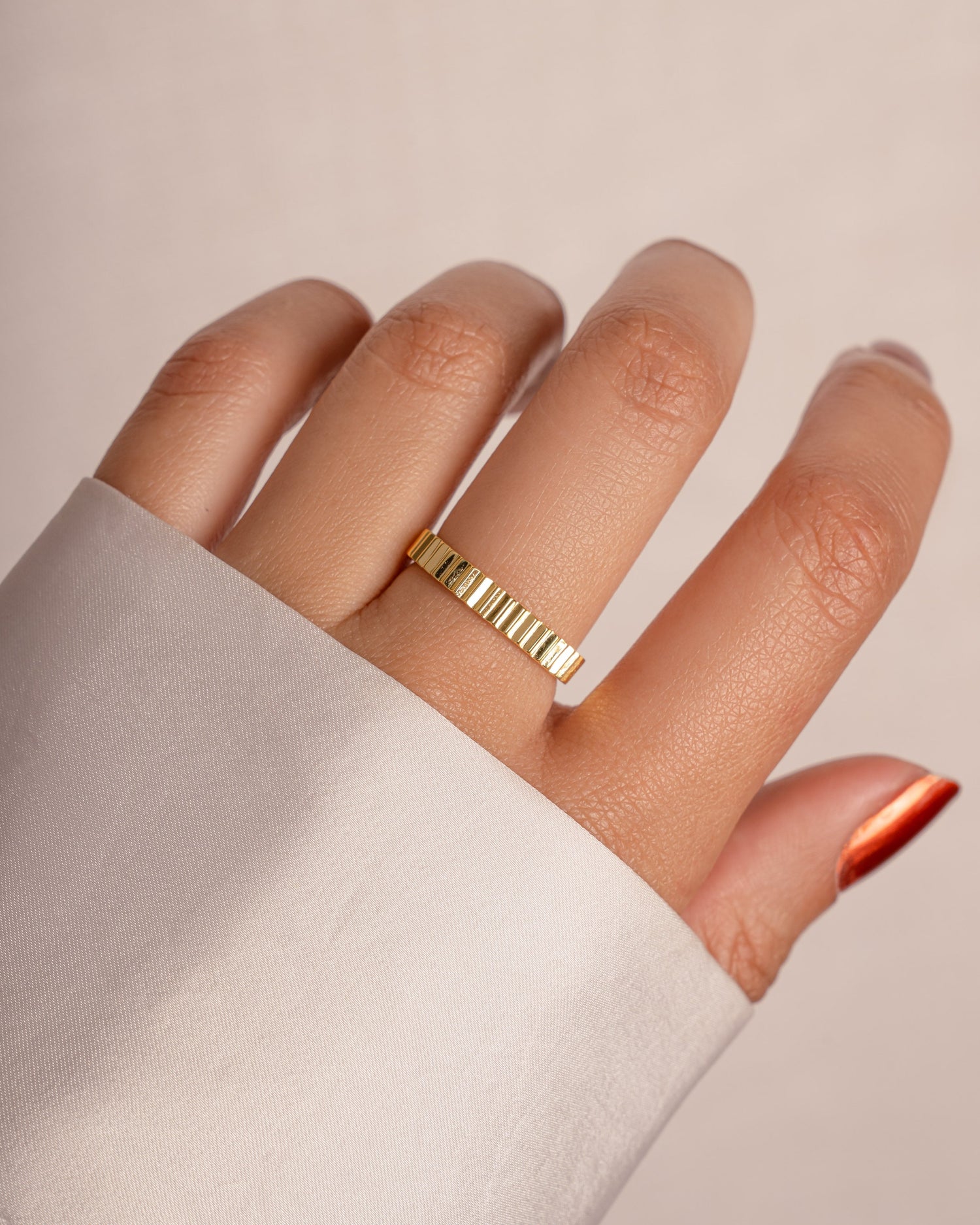 Gold ridged ring from Sami Jewels worn on a model's finger, showcasing its textured design and elegant style.