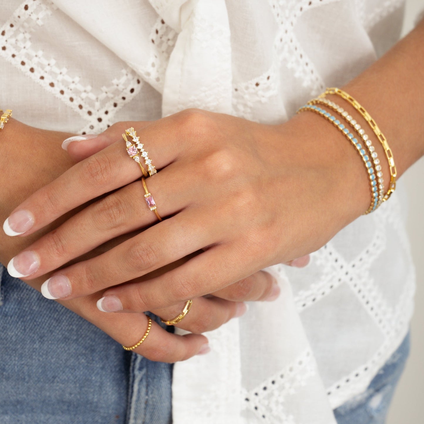stacking rings on a model wearing a rose baguette ring, a diamond eternity ring, and a pink cushion cut ring with pear side stones