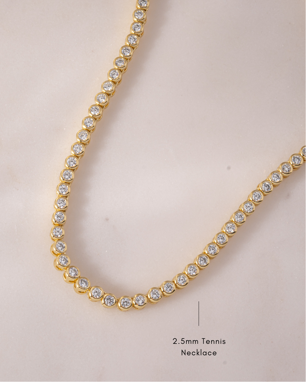 Gold round bezel diamond tennis necklace with 2.5mm diamonds, displayed flat showcasing its elegant design.