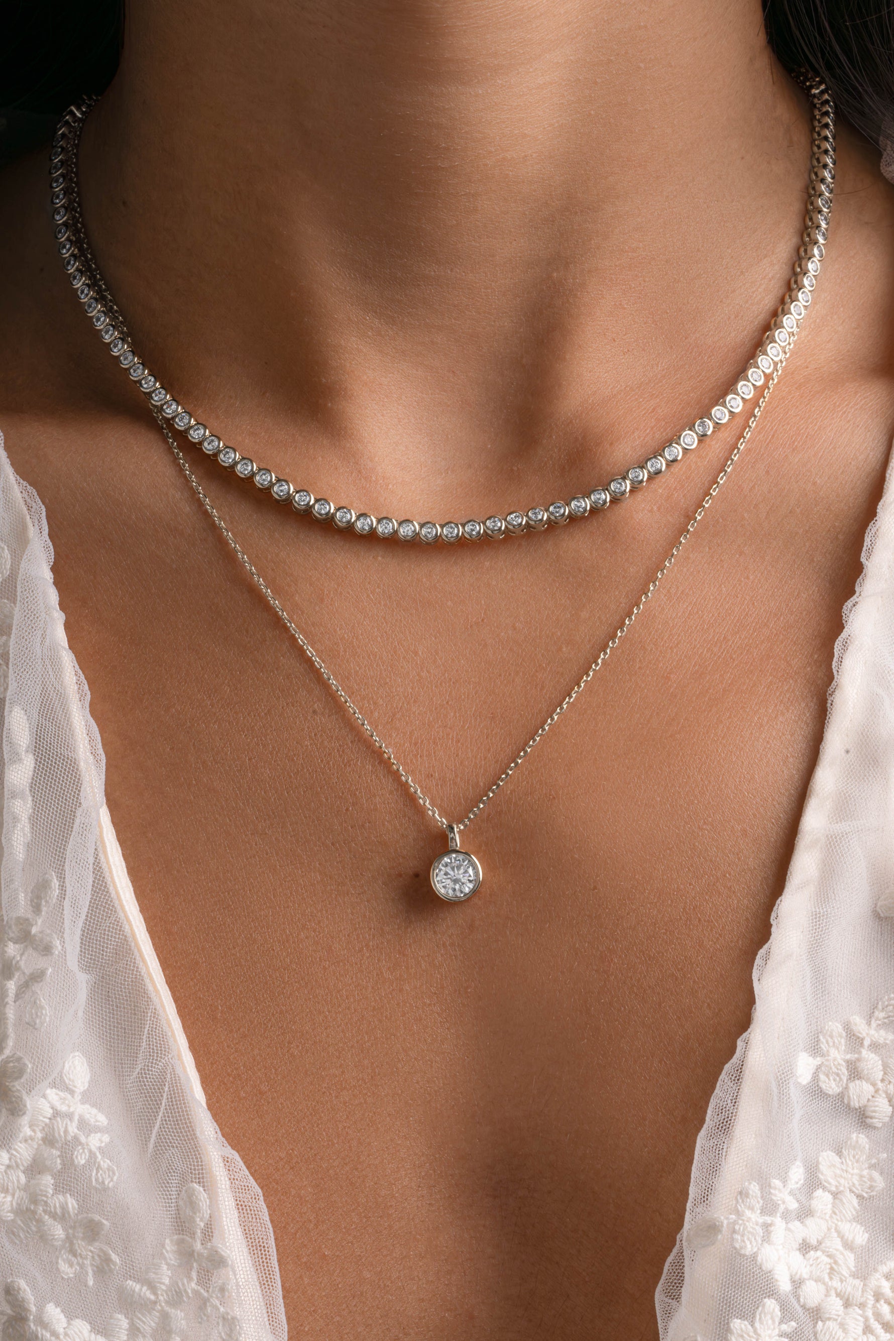 Silver round bezel necklace and tennis necklace bundle by Sami Jewels, featuring elegant jewelry pieces on a model.