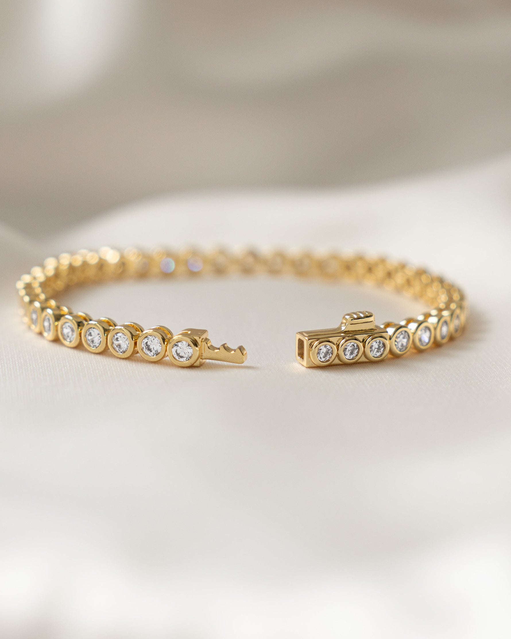 round bezel diamond tennis bracelet, 3mm in gold showing box clasp closure style