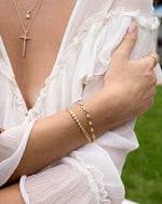 round bezel diamond tennis bracelet, 3mm in gold on a modesl wrist stacked with other gold jewelry