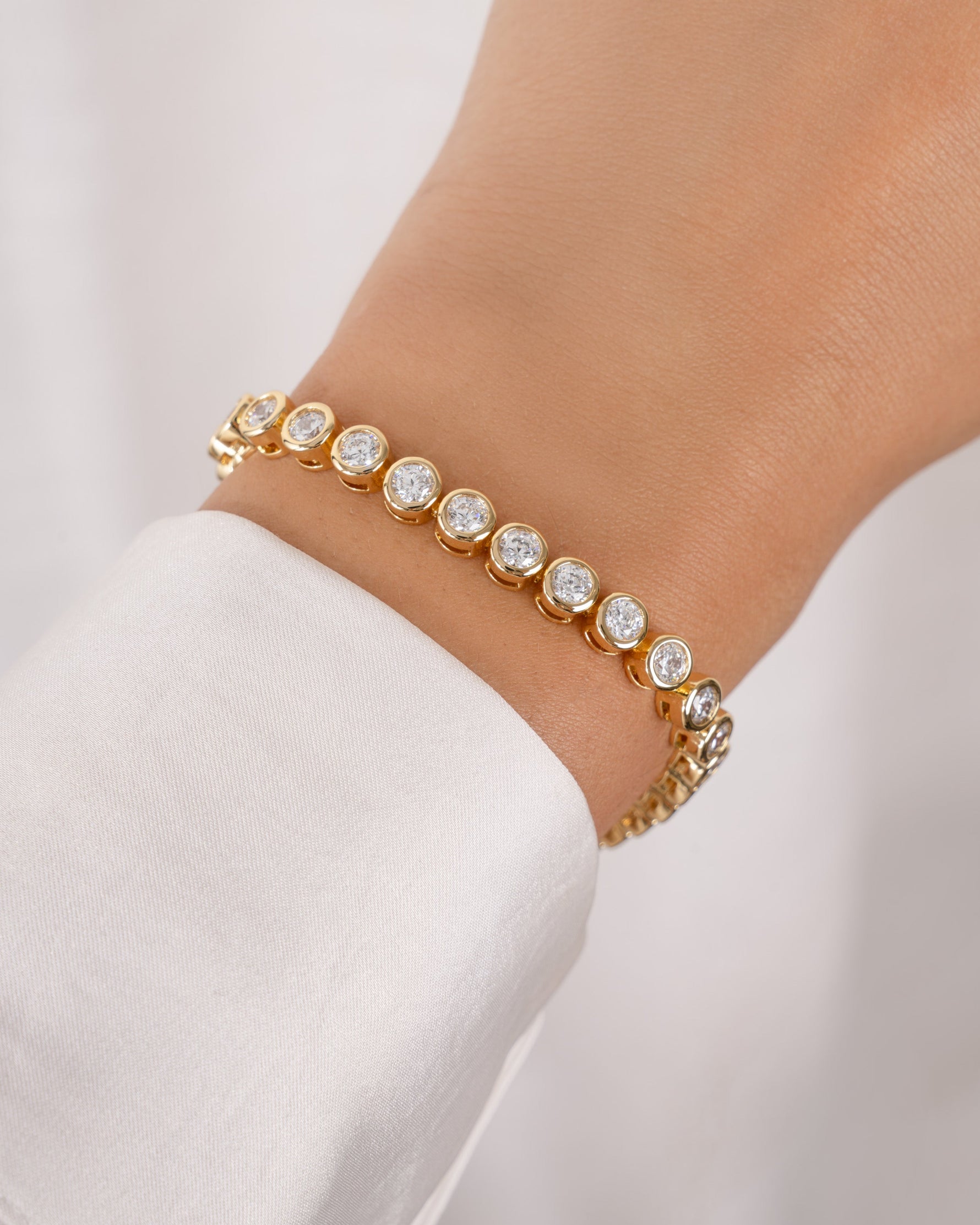 round bezel diamond tennis bracelet in 4mm gold on models wrist