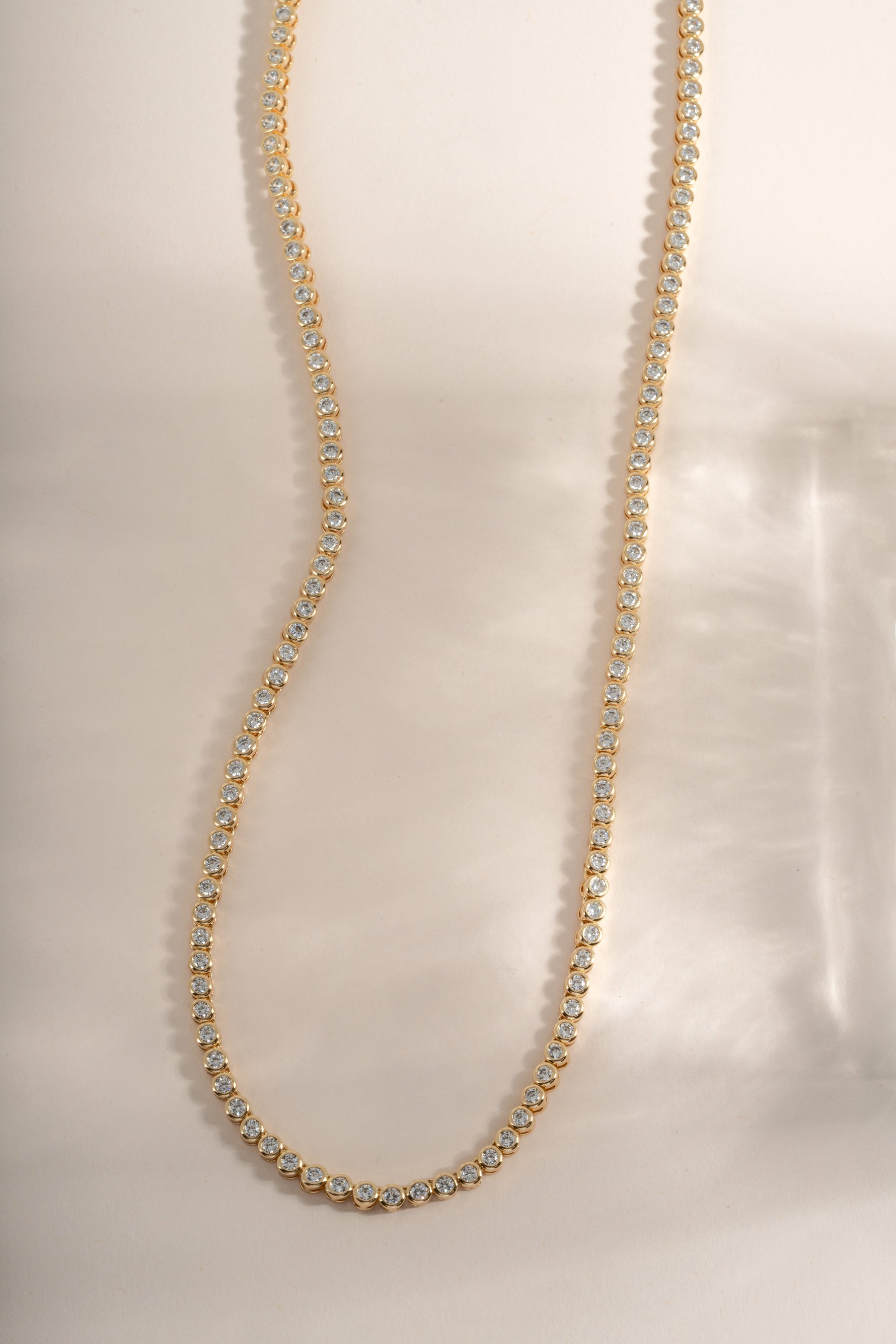 Gold round bezel tennis necklace bundle by Sami Jewels featuring a classic chain design and sparkling gemstone accents.
