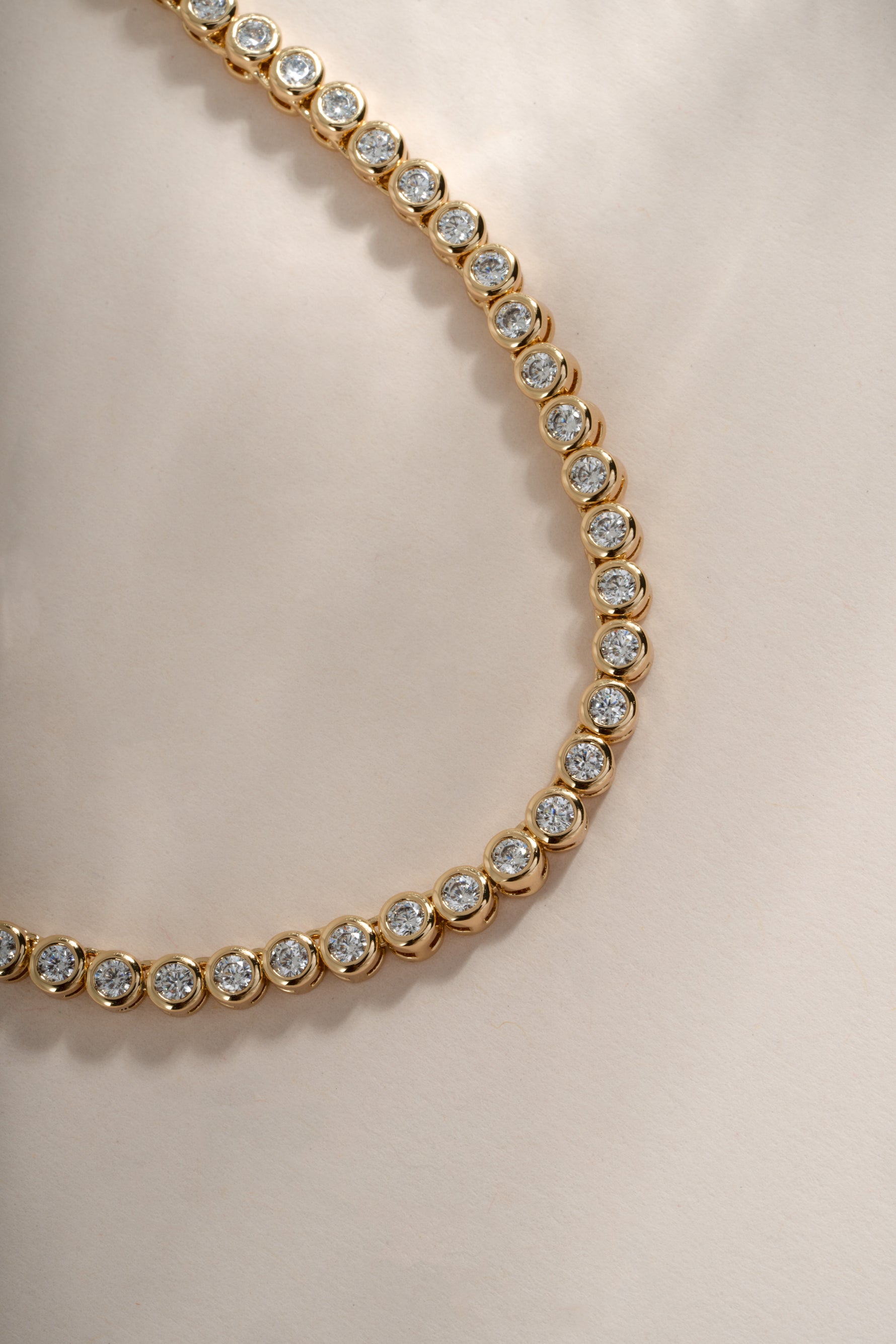 Close-up of a 2.5mm gold round bezel tennis necklace by Sami Jewels, showing the detailed beaded chain and smooth bezel settings.