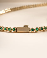 Detail of bezel-set round green stones on emerald tennis necklace, view 1