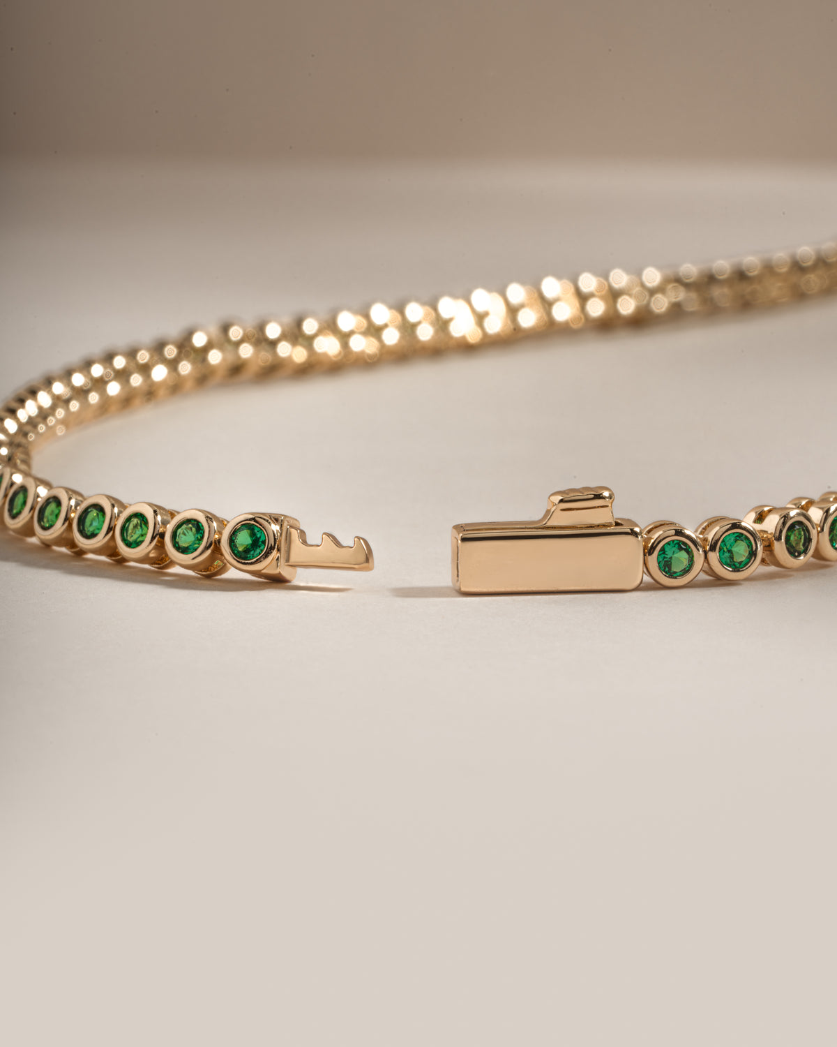 Detail of bezel-set round green stones on emerald tennis necklace, view 2