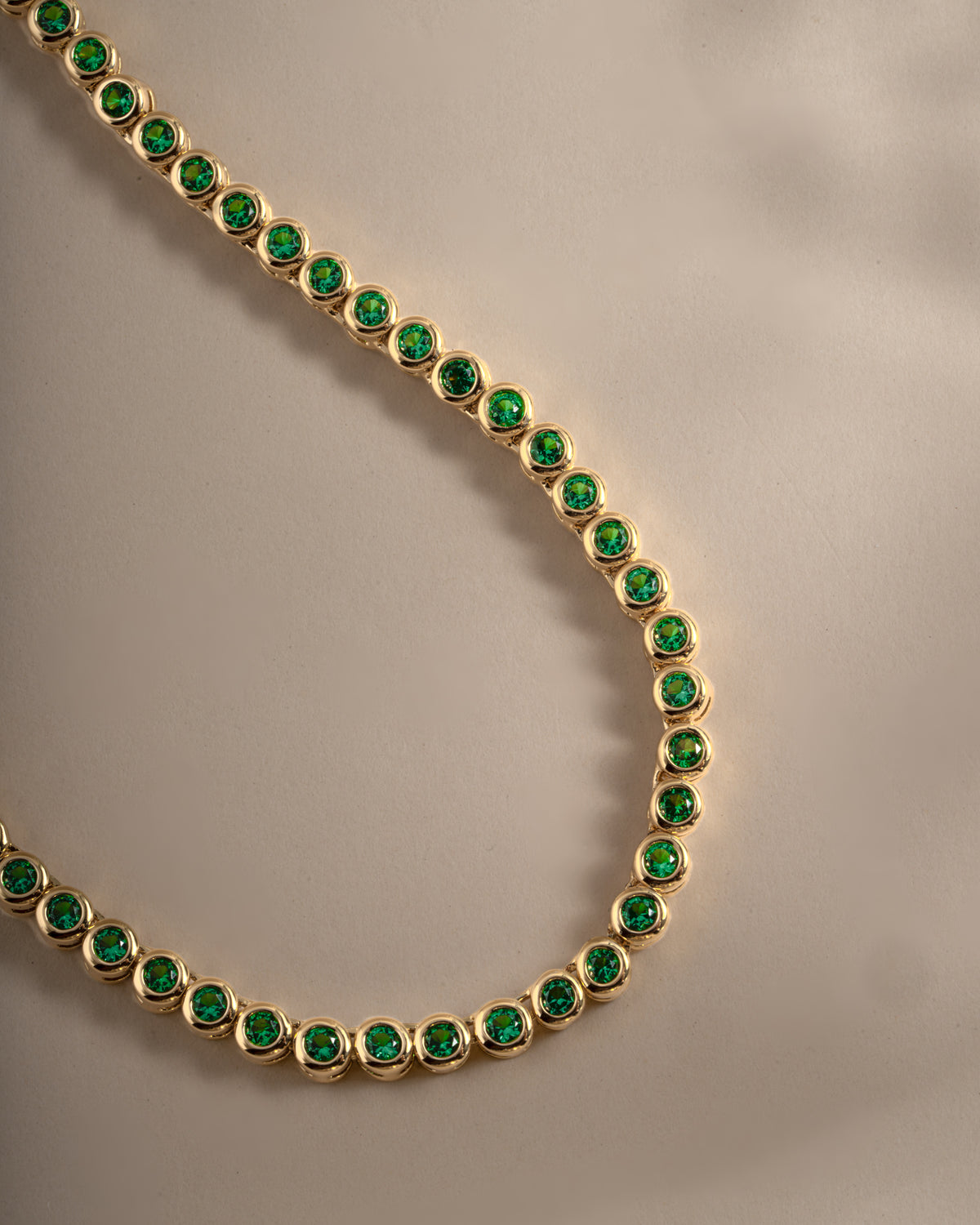 Detail of bezel-set round green stones on emerald tennis necklace, view 4