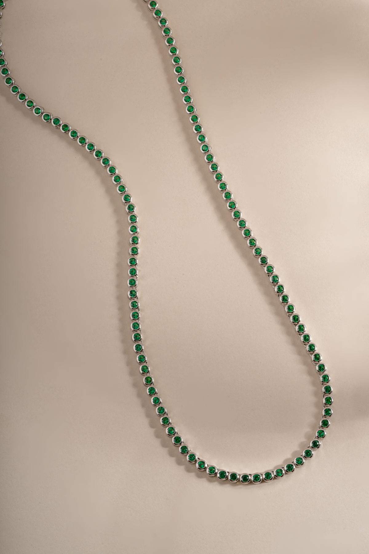 Detail of bezel-set round green stones on emerald tennis necklace, view 5