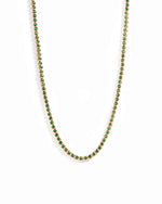 Gold plated round emerald tennis necklace on white background