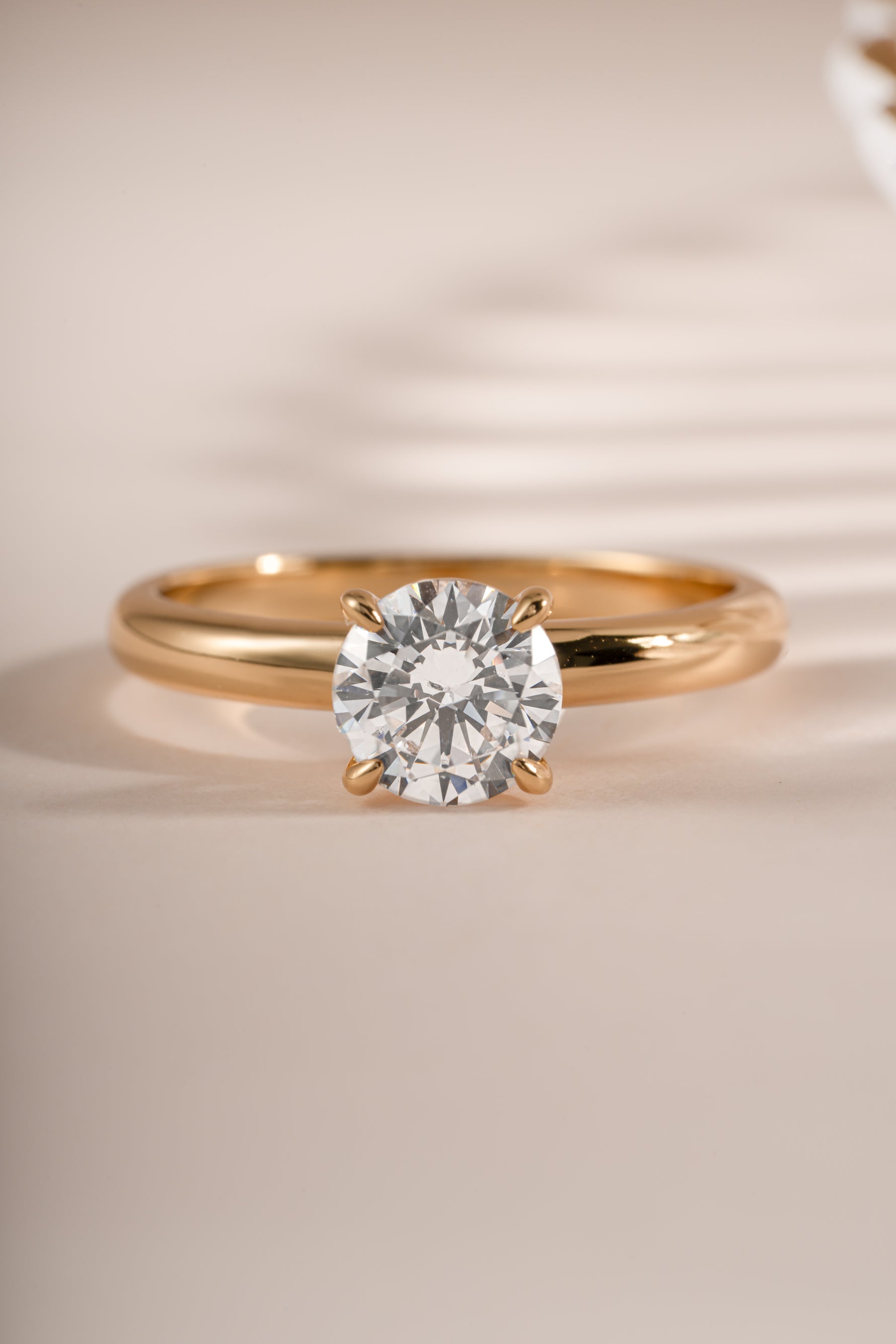 Close-up of Sami Jewels gold round solitaire ring showcasing a single sparkling gemstone on a smooth band.
