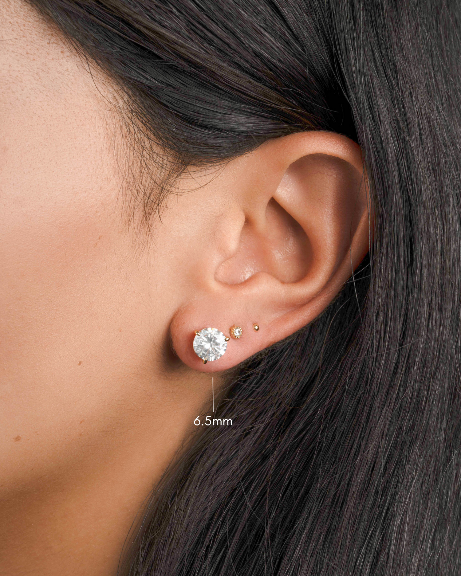 round solitaire stud earrings in gold, 6.5mm on models ear