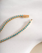 Round turquoise bezel tennis necklace by Sami Jewels featuring a gold box clasp closure and vibrant turquoise stones.
