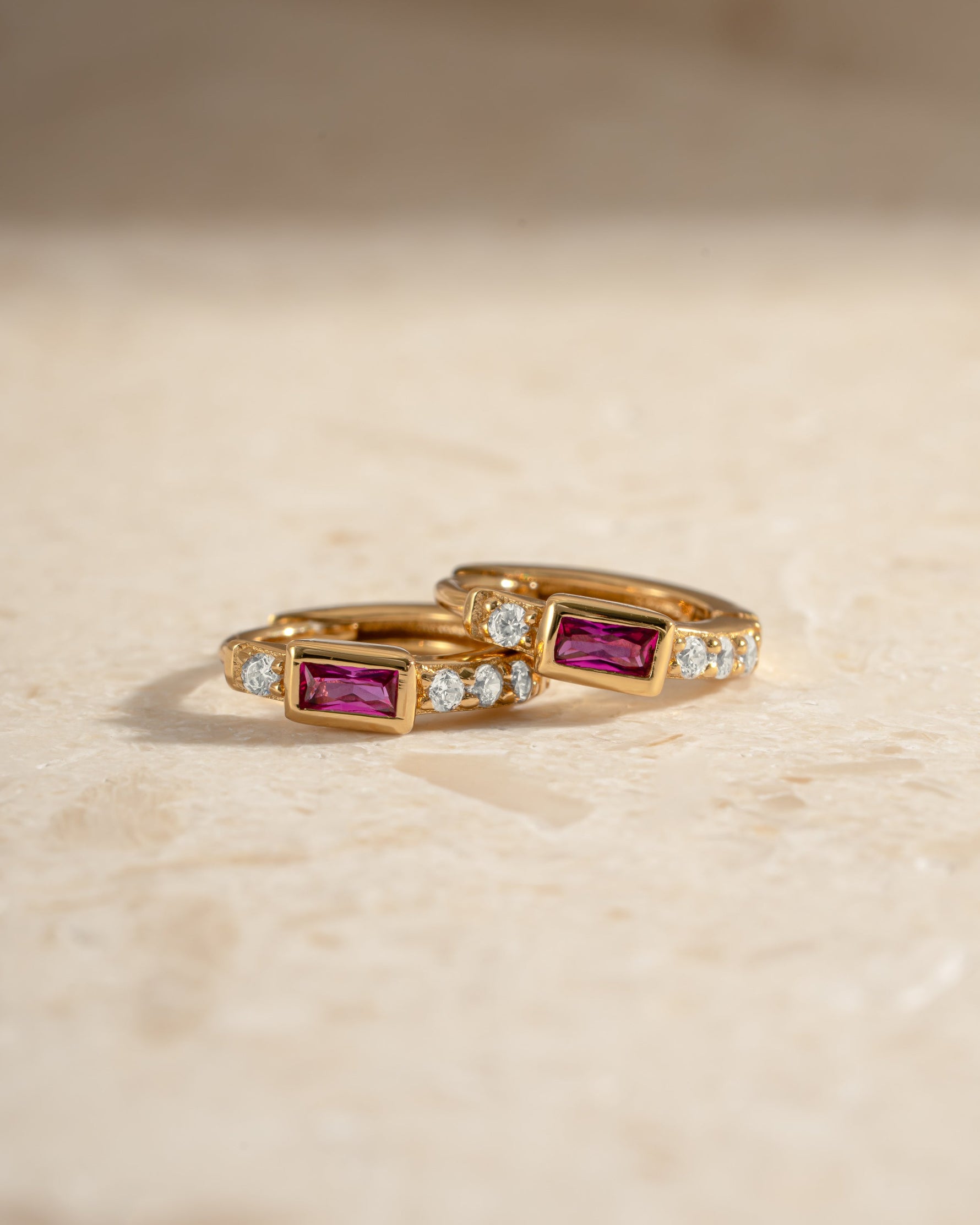Gold Ruby Baguette Huggie Earrings from Sami Jewels, close-up view showing sparkling rubies and sleek gold design.