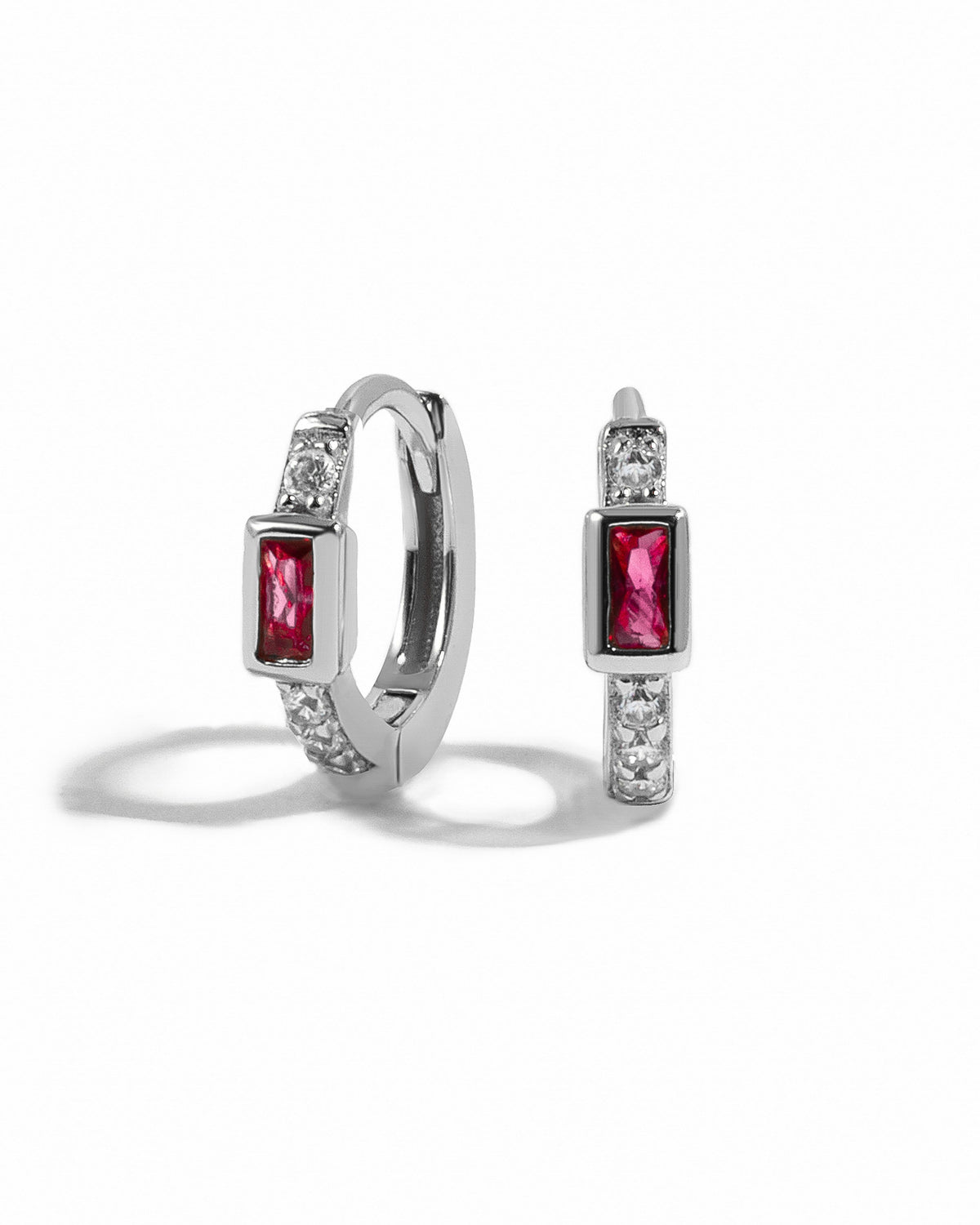 Sterling silver Ruby Baguette Huggie Earrings with vibrant red gemstones on a white background.