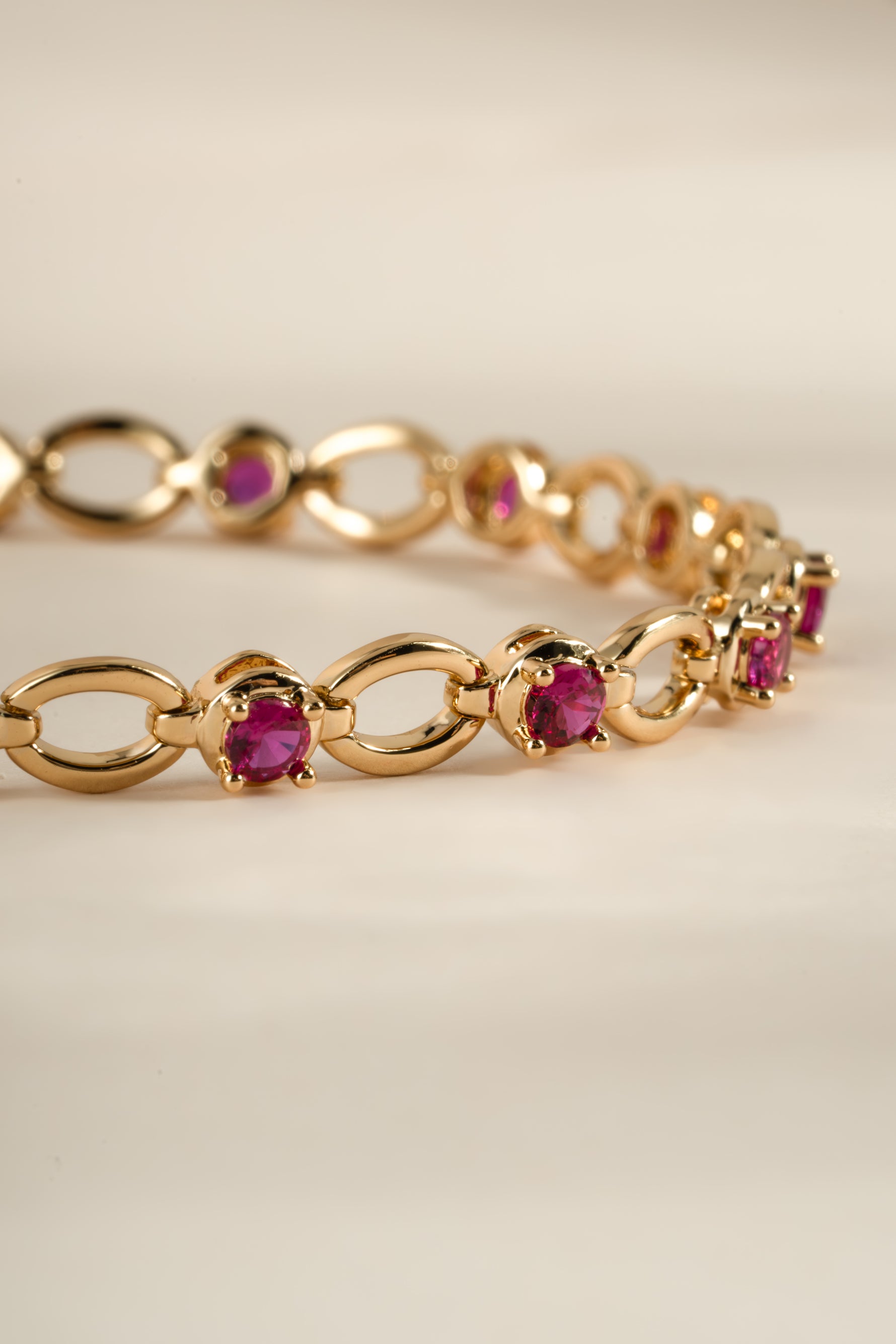 Close-up of Sami Jewels Ruby Lilly Tennis Bracelet featuring a gold chain with vibrant ruby stones.