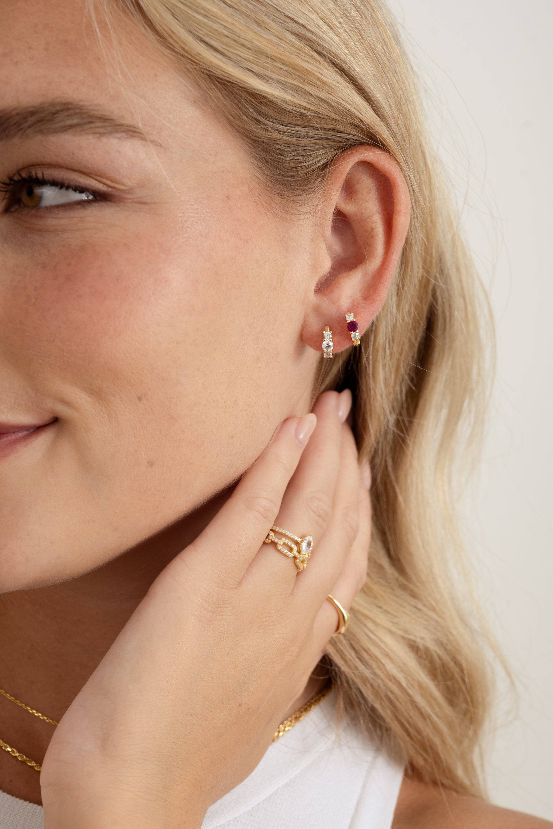 ruby three stone huggie earring in gold on model ear stack