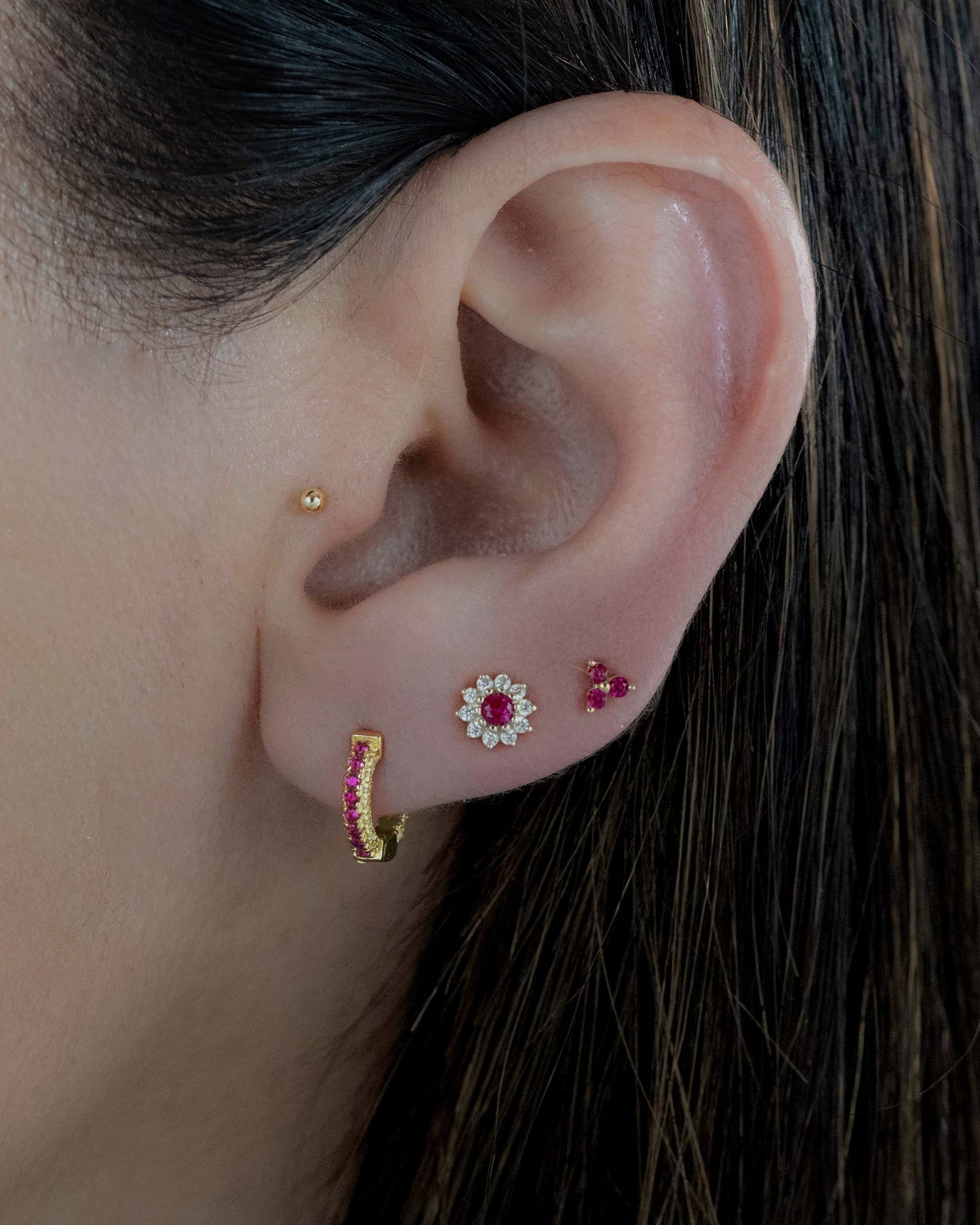 Model wearing gold dainty ruby flower stud earrings.
