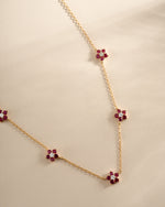 Gold necklace featuring a ruby flower charm from Sami Jewels, showcasing a delicate floral pendant design.