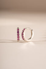 Sterling silver 7mm ruby-studded huggie earrings from Sami Jewels, angled view showing gemstone detail and sleek design.