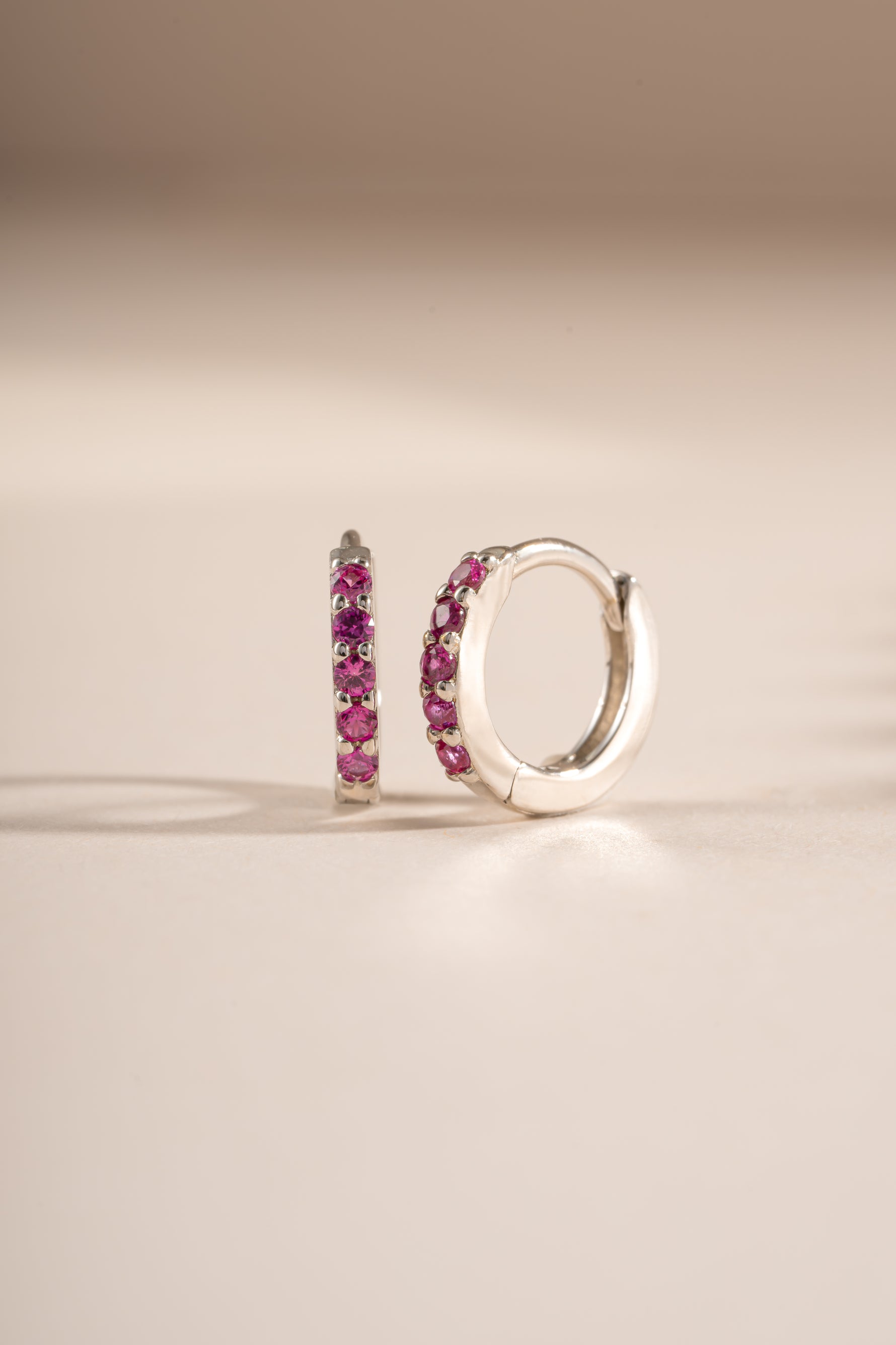 Sterling silver 7mm ruby-studded huggie earrings from Sami Jewels, angled view showing gemstone detail and sleek design.