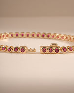 Gold Ruby Bezel Tennis Bracelet by Sami Jewels with box clasp and detailed close-up of the vibrant ruby stones.