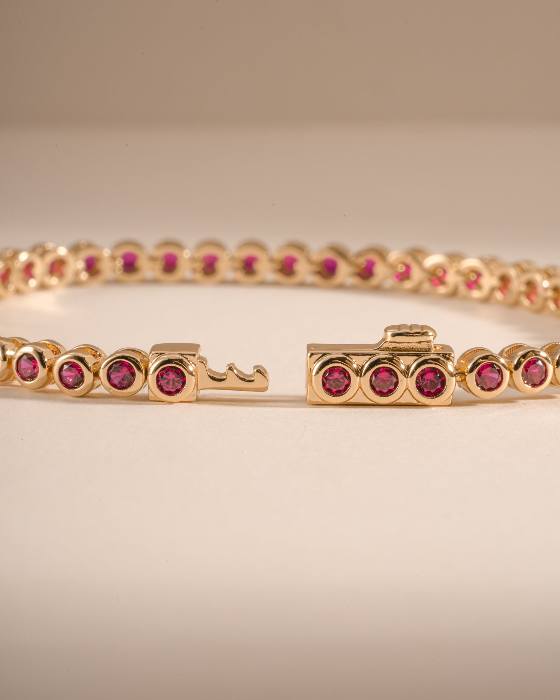 Gold Ruby Bezel Tennis Bracelet by Sami Jewels with box clasp and detailed close-up of the vibrant ruby stones.