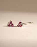 Sami Jewels Tiny Ruby 3 Stone Stud Earrings in sterling silver with three vibrant rubies, angled view showcasing the design.