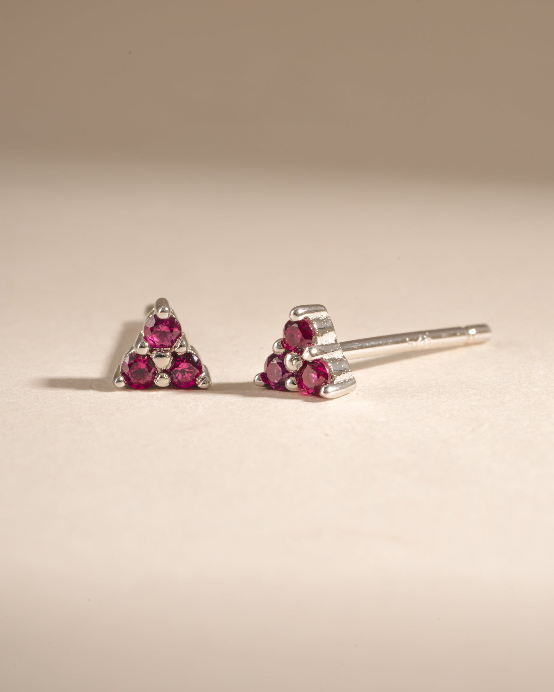 Sami Jewels Tiny Ruby 3 Stone Stud Earrings in sterling silver with three vibrant rubies, angled view showcasing the design.