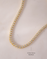 closeup image of gold tennis necklace with flush bezel stones