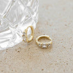 minimalist gold hoop earrings propped up against a glass