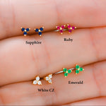 Four pairs of earrings labeled Sapphire, Ruby, Emerald, and White CZ on a hand.
