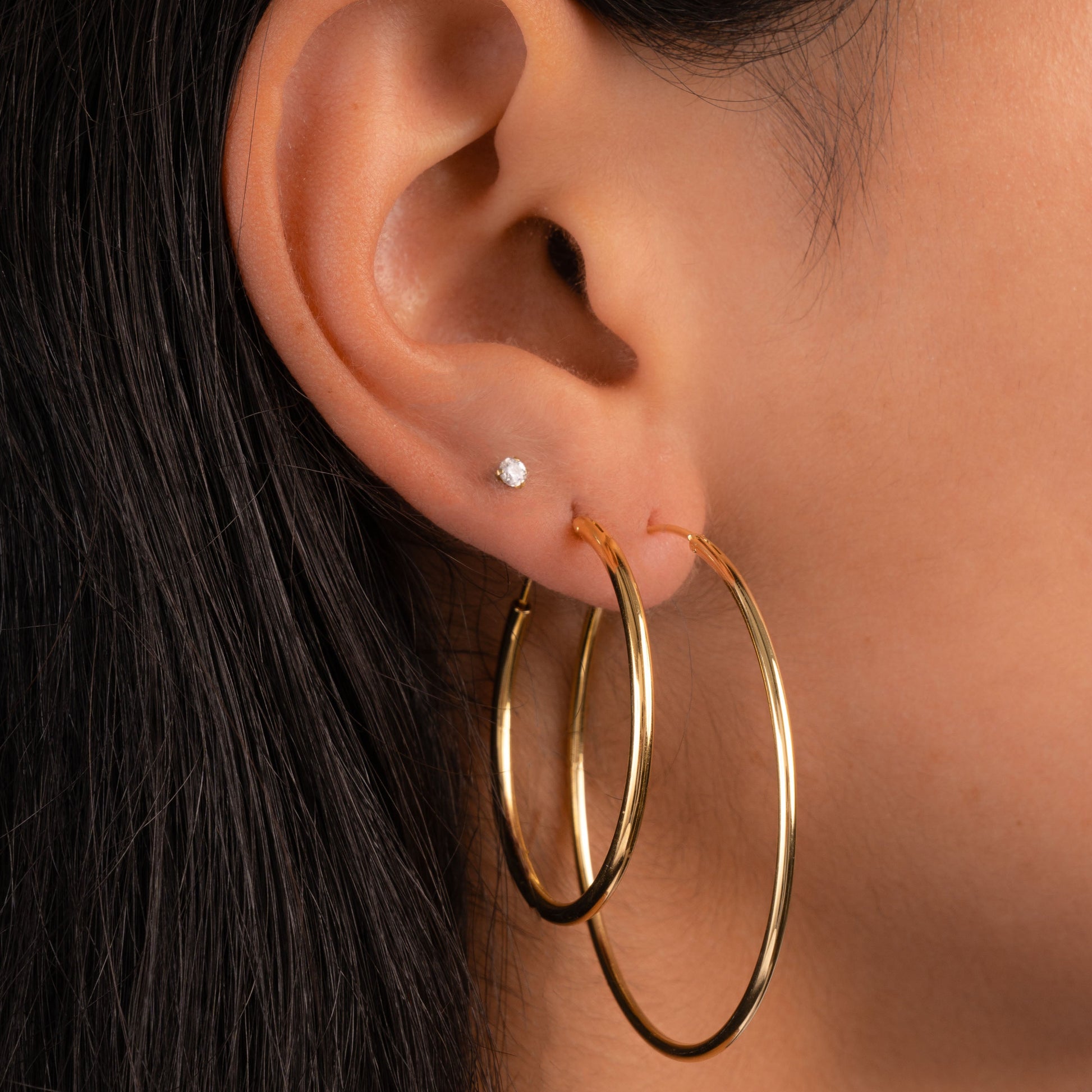 Model wearing large hoop earrings in different sizes