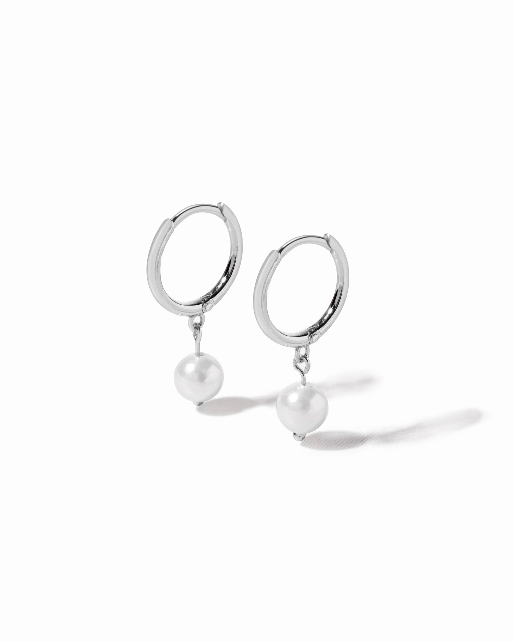 Silver hoop earrings with pearl charm on a white background