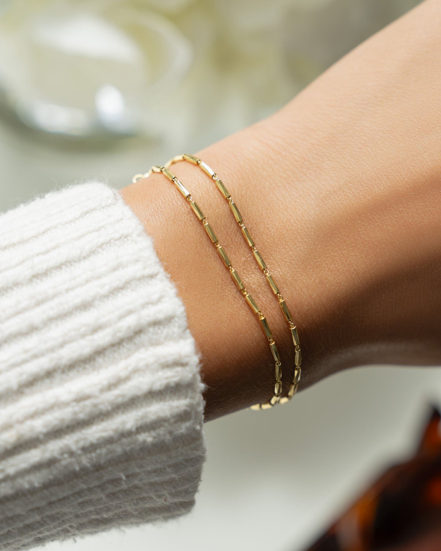 Model wearing gold chain adjustable bracelet with a beaded bracelet design