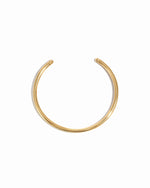 Over head image of a gold arm cuff bangle bracelet on a white background