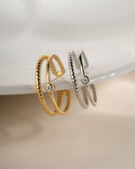 Gold plated toe ring and sterling silver toe ring hanging off a plate with a bezel set cubic zirconia stone and an adjustable ring design