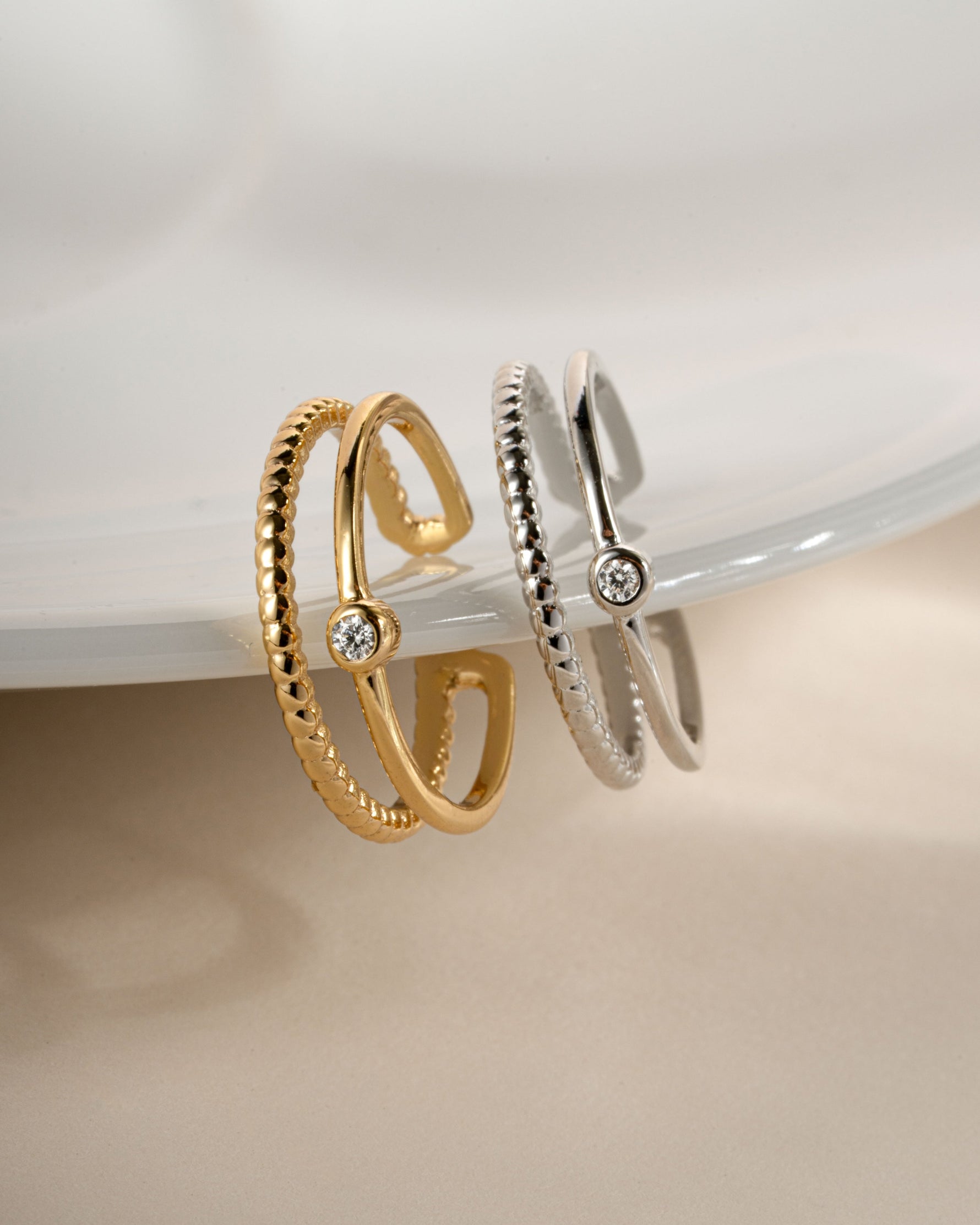 Gold plated toe ring and sterling silver toe ring hanging off a plate with a bezel set cubic zirconia stone and an adjustable ring design