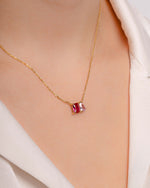 model wearing emerald cut and pear cut multi stone diamond necklace with rose quartz birthstone and ruby birthstone