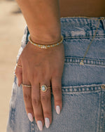 closeup image of model wearing gold and aquamarine jewelry featuring aquamarine tennis bracelet