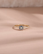 Gold minimalist ring with a blue gemstone on a beige background